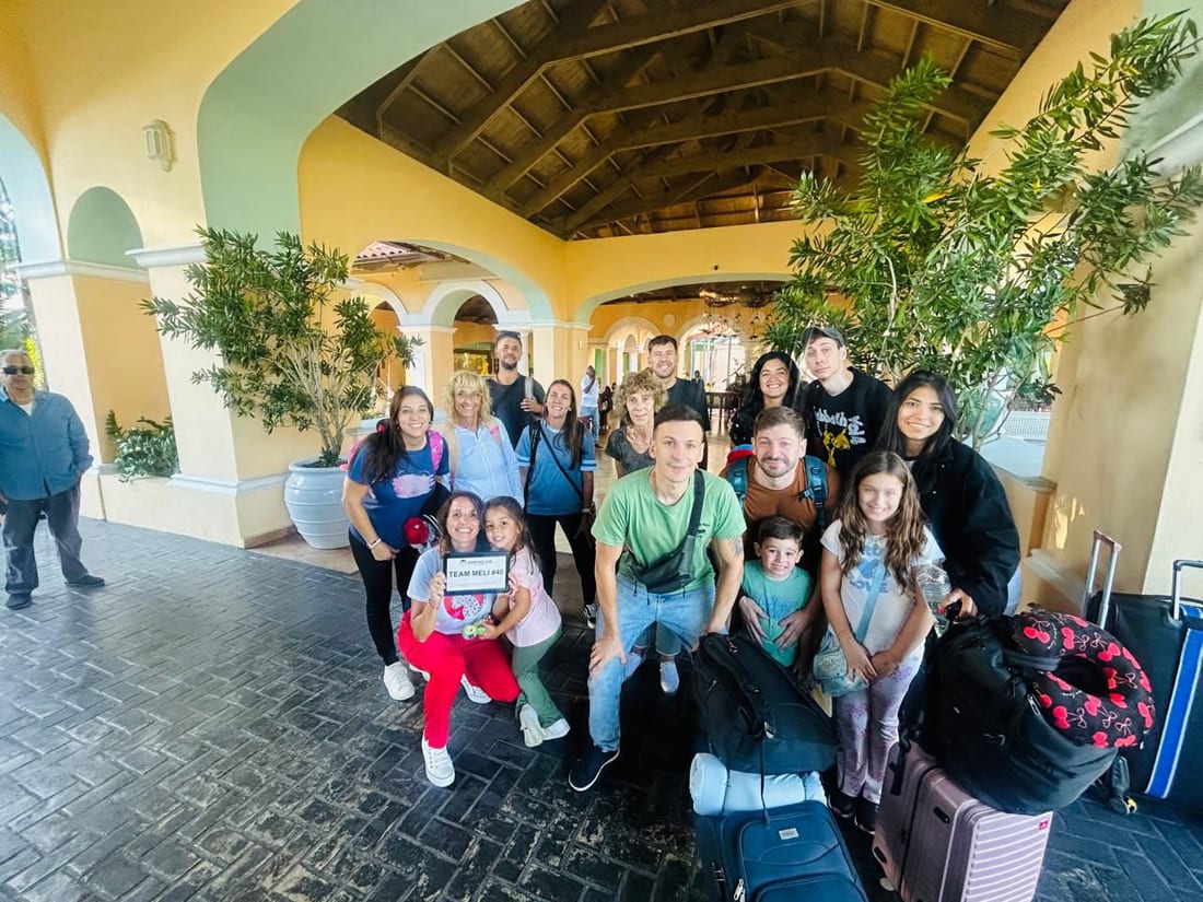 Grupo numeroso recibido en un resort con cartel de bienvenida